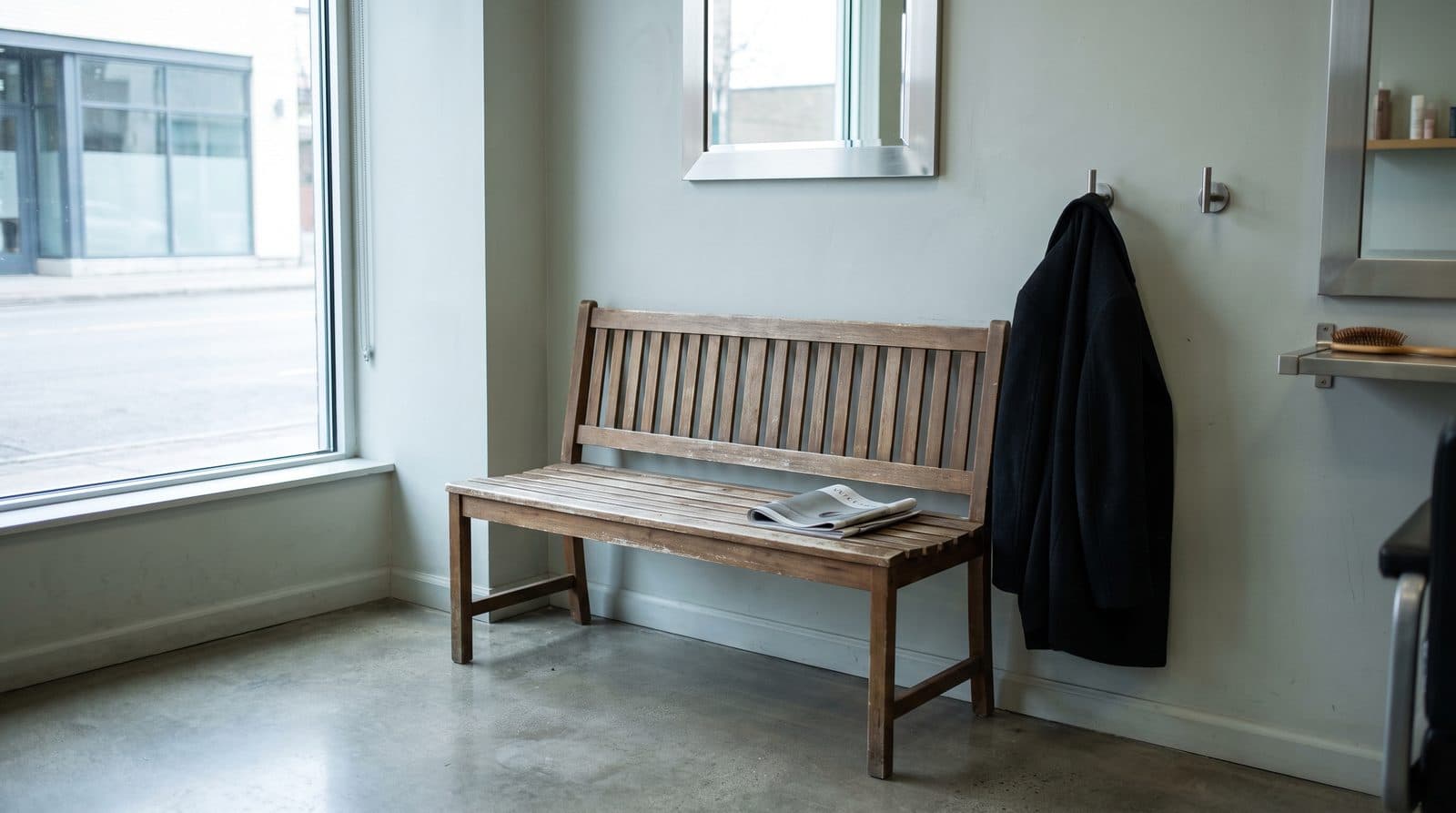 The waiting corner: a wooden bench under the front window, a coat on a hook