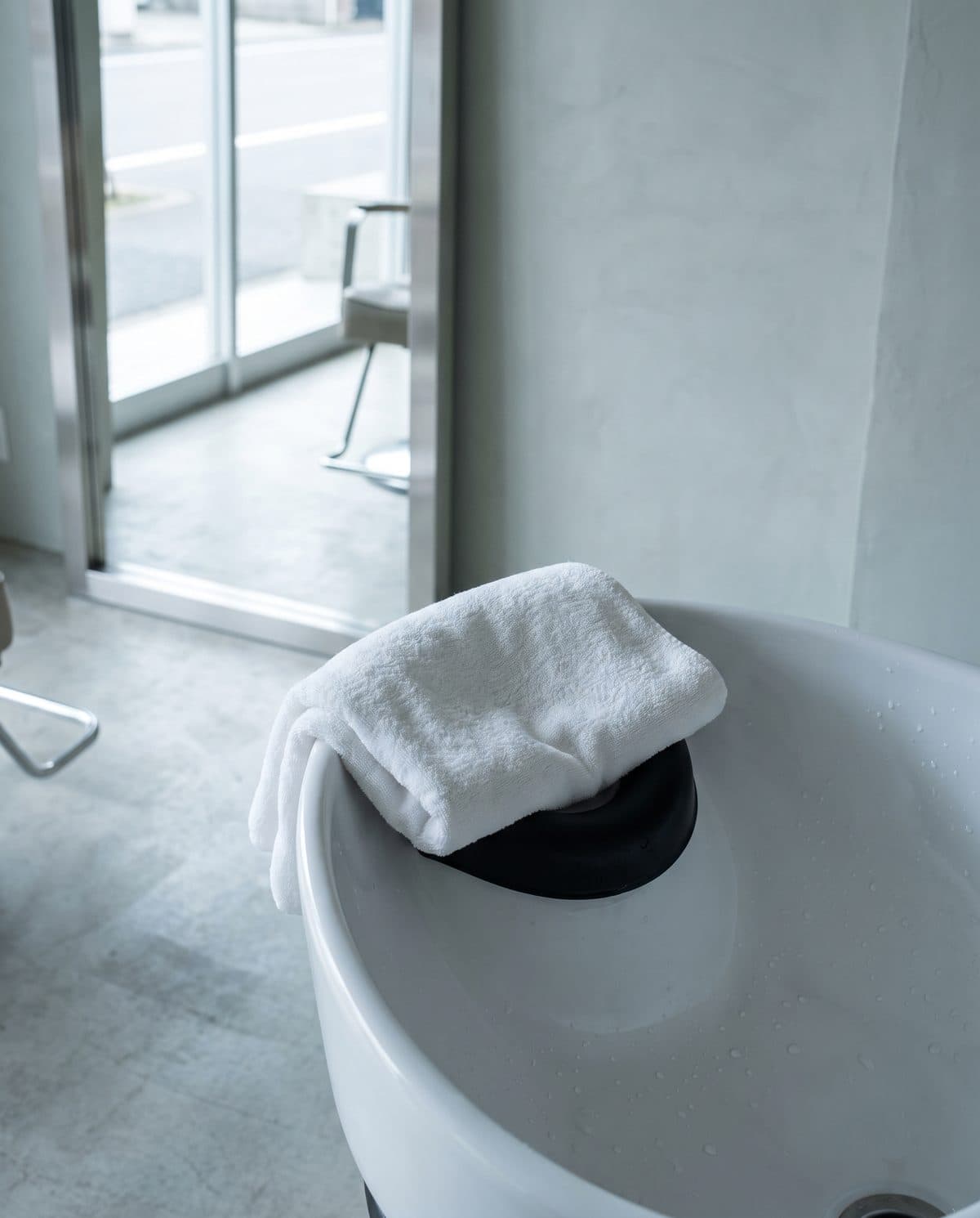 A porcelain shampoo basin with a folded towel over the neck rest