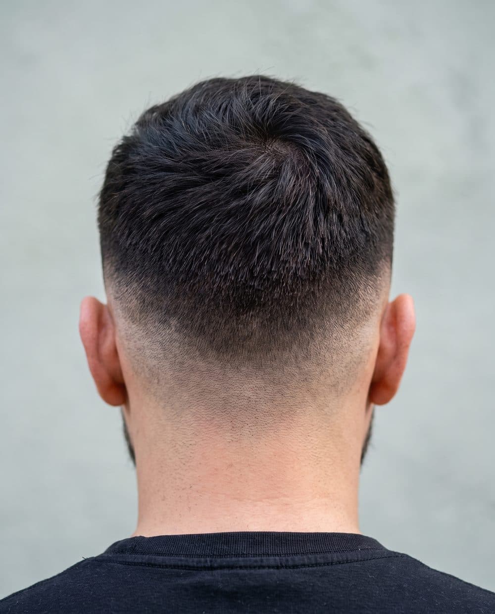 A short clipper fade photographed close at the back of the head, the gradient running from near skin at the neck into longer hair with no visible step